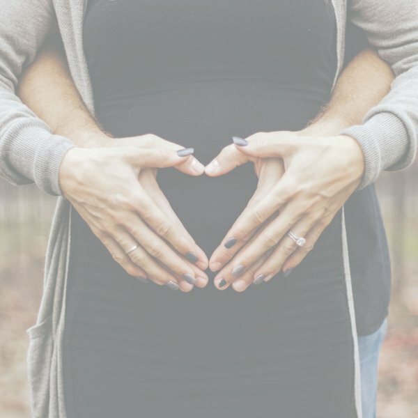 couple making heart with hands on woman's belly